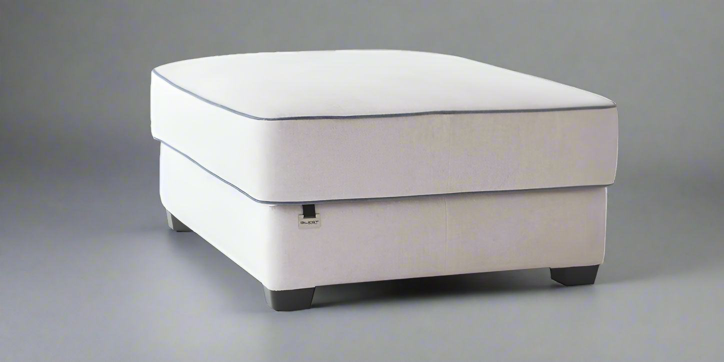 A white upholstered pouf with a cushioned top, equipped with wheels at the base, presumably for mobility or storage purposes.